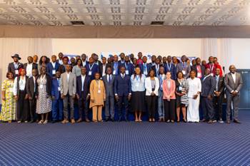 A large group photo of conference attendees wearing badges.